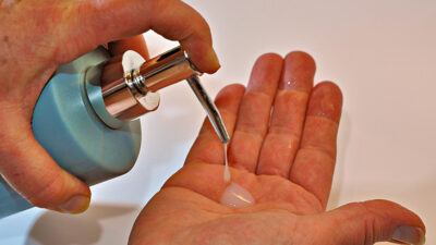 Närbild på två händer. Någon tar tvål från en tvålpump.