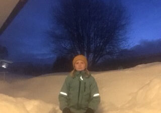 En elev står framför en snöhög.