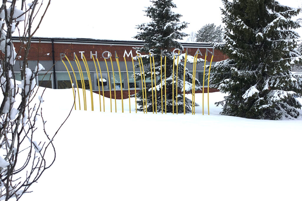 Bokstäver som bildar namnet Pitholmsskolan står på stänger i snön.