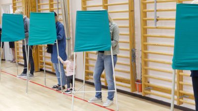 Bild på människor som röstar bakom skärmar.